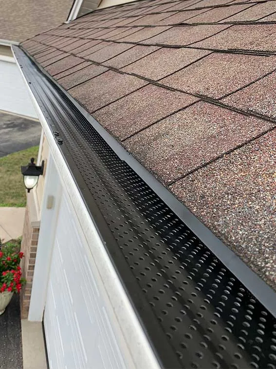 A seamless gutter with a leaf guard along a white fascia