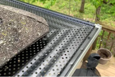 A close-up of a black gutter guard keeping debris out