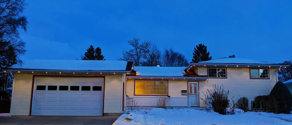 A single-story home with warm permanent roofline lighting in winter
