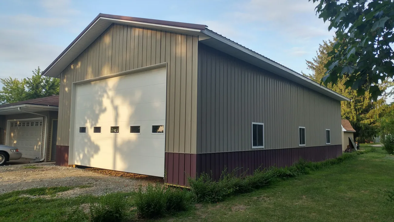 An agricultural shop building with a tan and burgundy metal roof