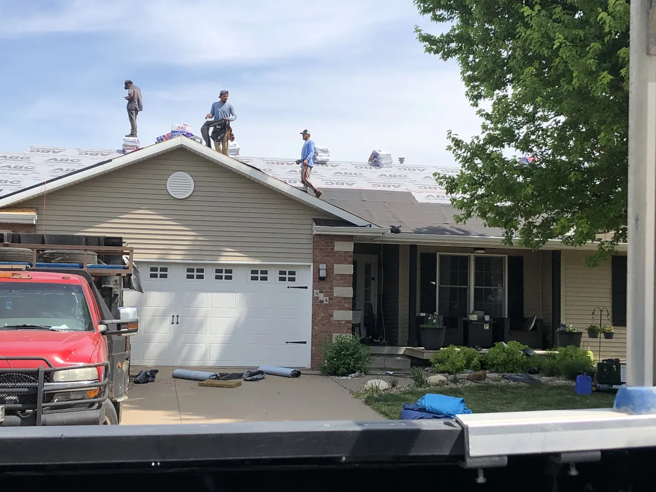A New Summit Roofing crew installing a roof with the company truck on site