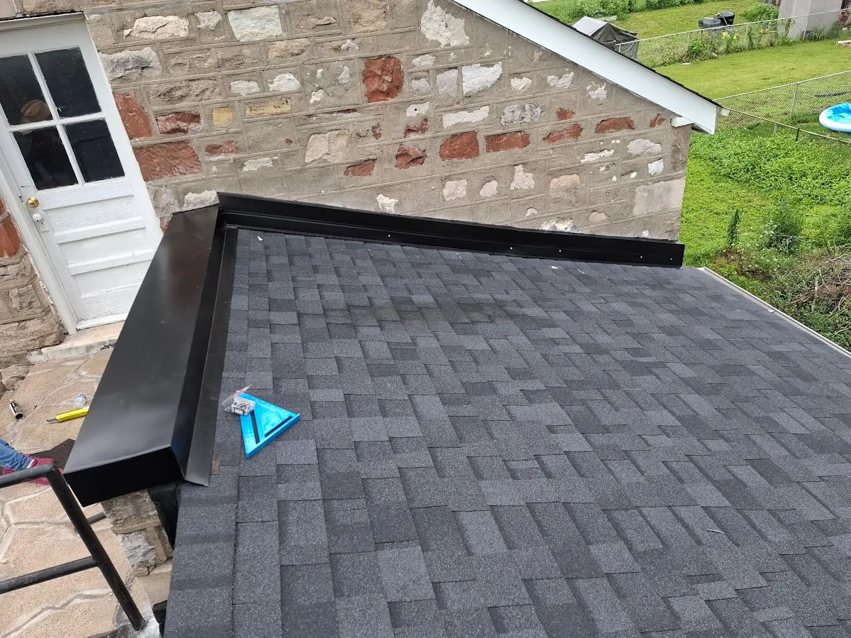 A low-slope roof section with fresh flashing repaired by New Summit Roofing