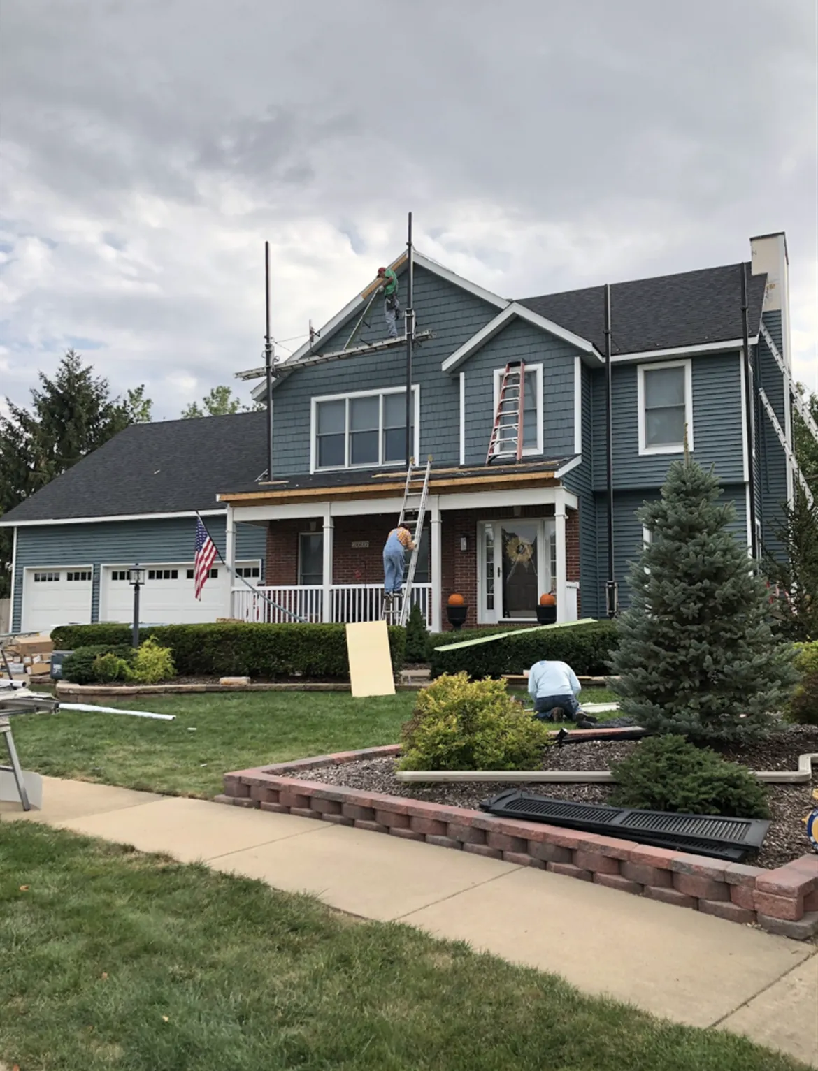 A blue-gray two-story home with new siding and a covered porch