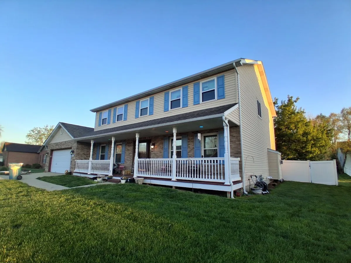 A gray two-story home getting new siding, boom lift on site