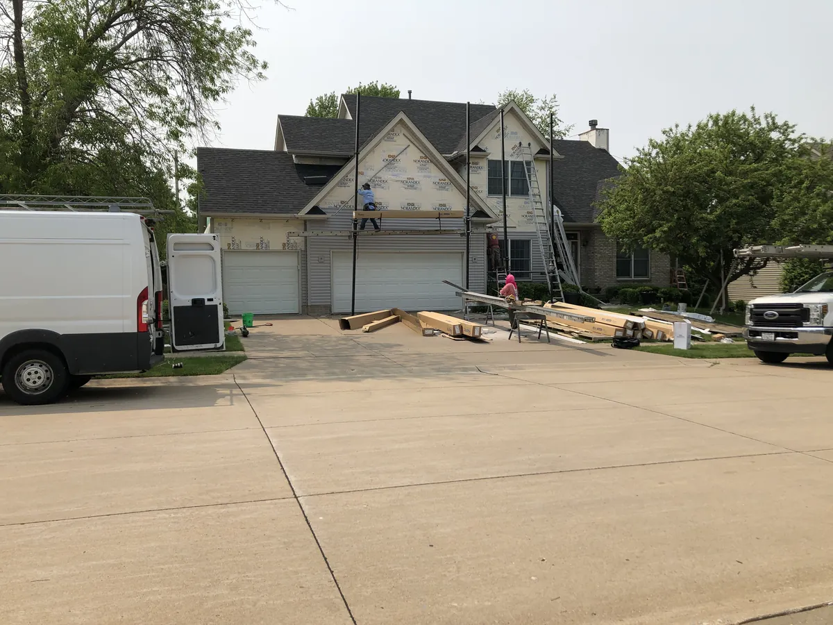 A gray home with new siding and the New Summit Roofing van in the driveway