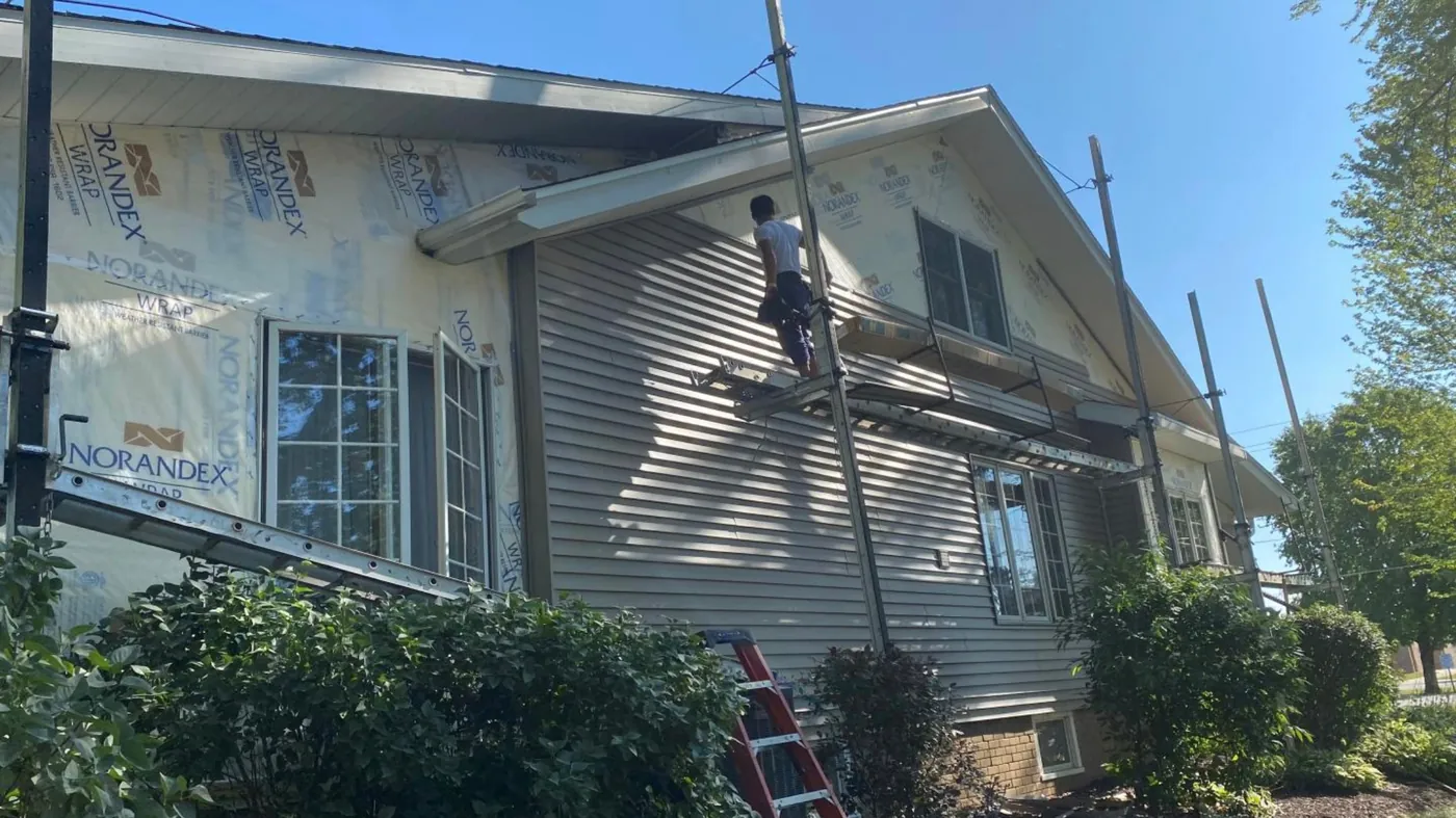 A New Summit Roofing crew member installing siding
